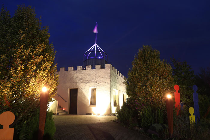 Die Miniburg am Mastholter See erstrahlt beim dritten Burgleuchten in bunten Farben. Viele Arrangements auf dem Areal sorgen 