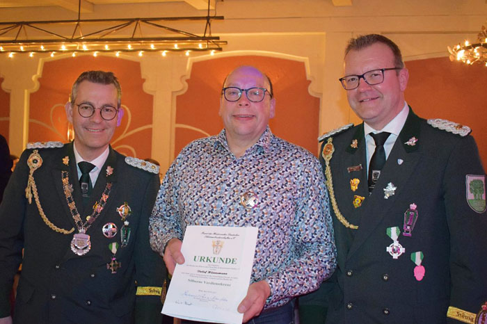 Die beiden Brudermeister Klaus Schnieder (l.) und Dirk Meier (r.) überreichen Detlev Hünemann das Silberne Verdienstkreuz.