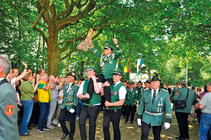 Ein Triumphmarsch des glücklichen Königs durch die jubelnden Zuschauermassen auf den Schultern seiner Spielmannszugkollegen